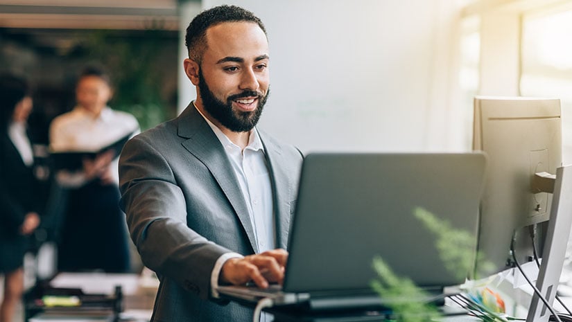 Businessman with beard standing at desk with laptop