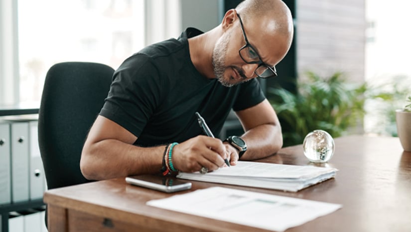 Mature businessman filling out paperwork at his desk in a modern office