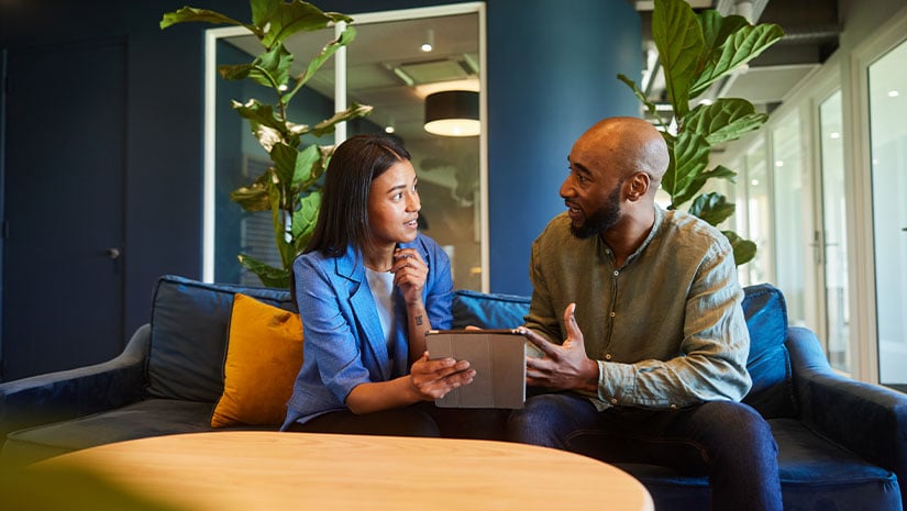 Businesspeople talking over a tablet while sitting on a sofa