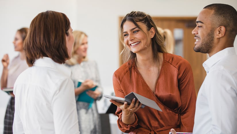 Cheerful young colleagues discussing with digital tablet