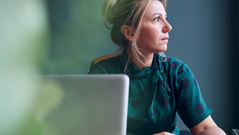 Thoughtful businesswoman looking away sitting in board room at office